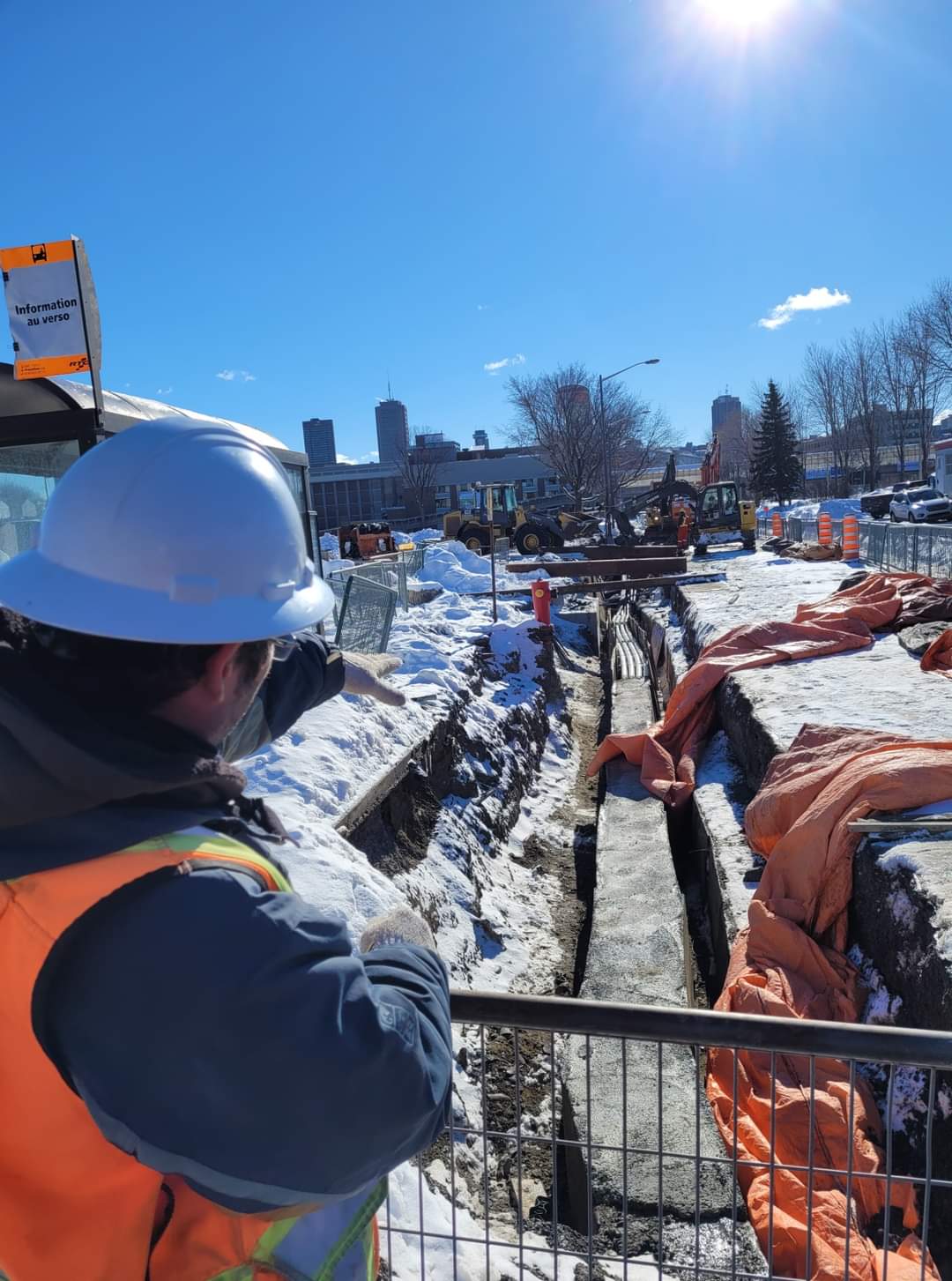 Relevé d’arpentage en hiver près d’une tranchée sur un chantier urbain.