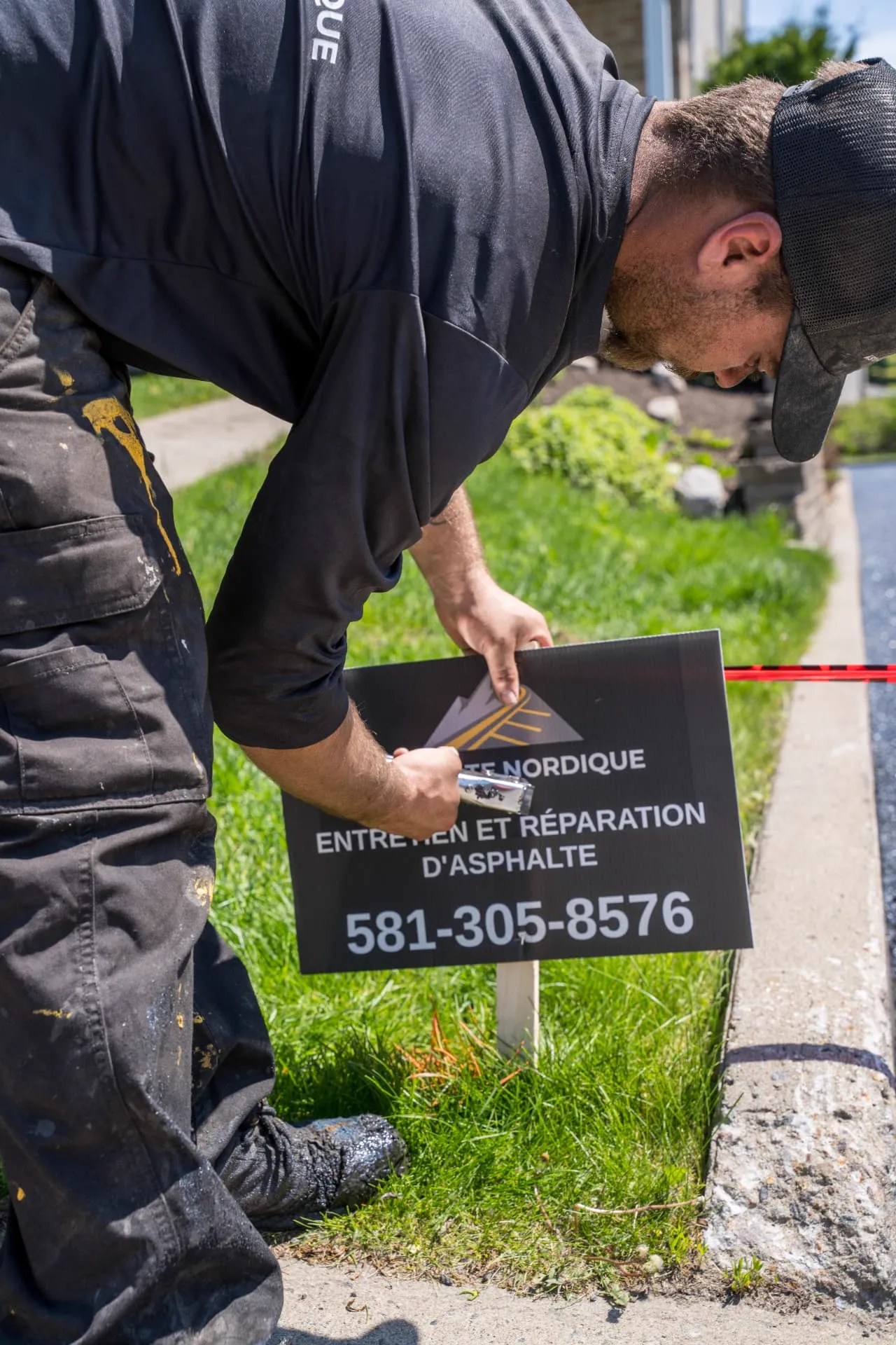 Installation de la pancarte Asphalte Nordique devant un chantier terminé