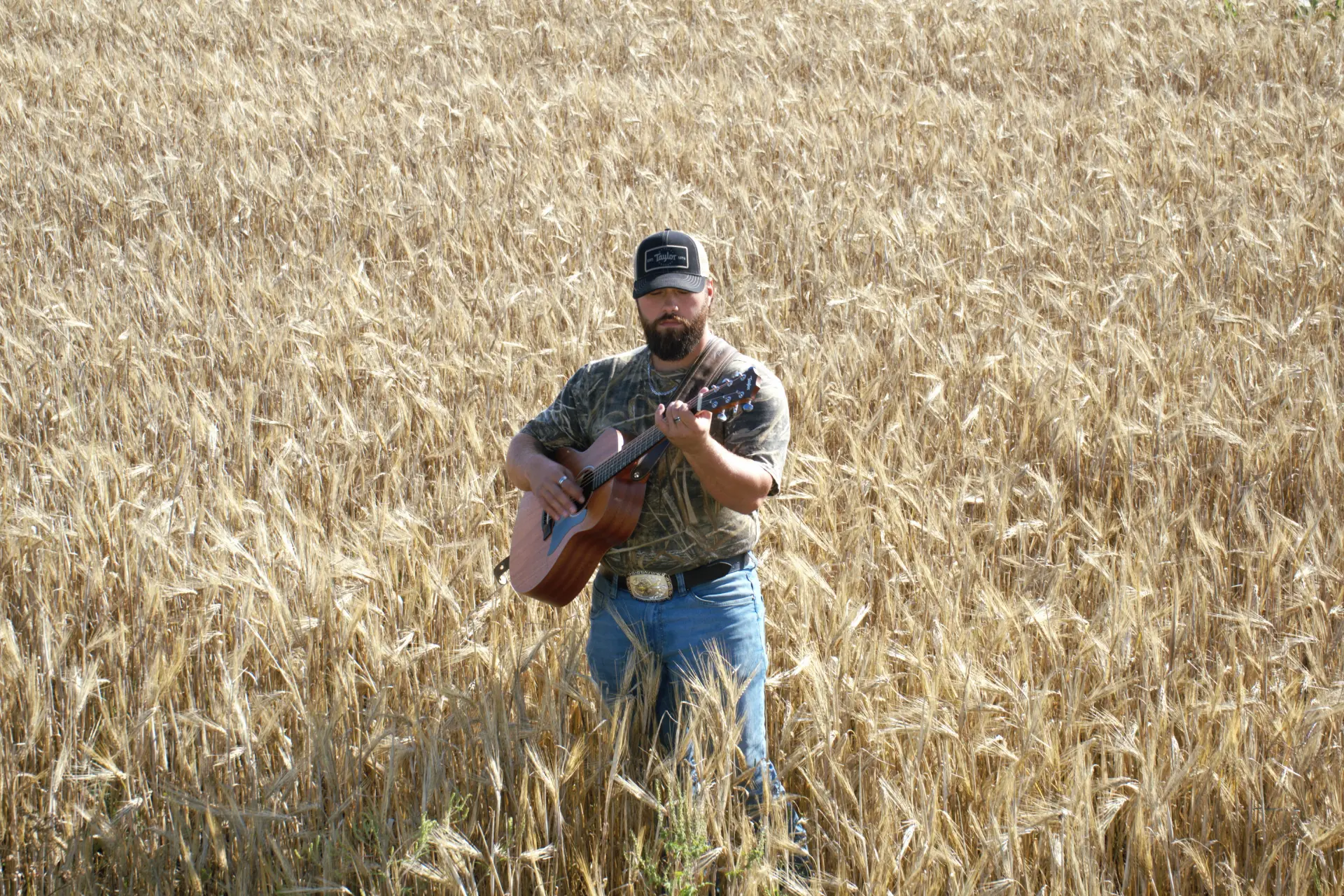 Arpin Lépine avec sa guitare dans un champ de blé à Saint-Félix-de-Valois