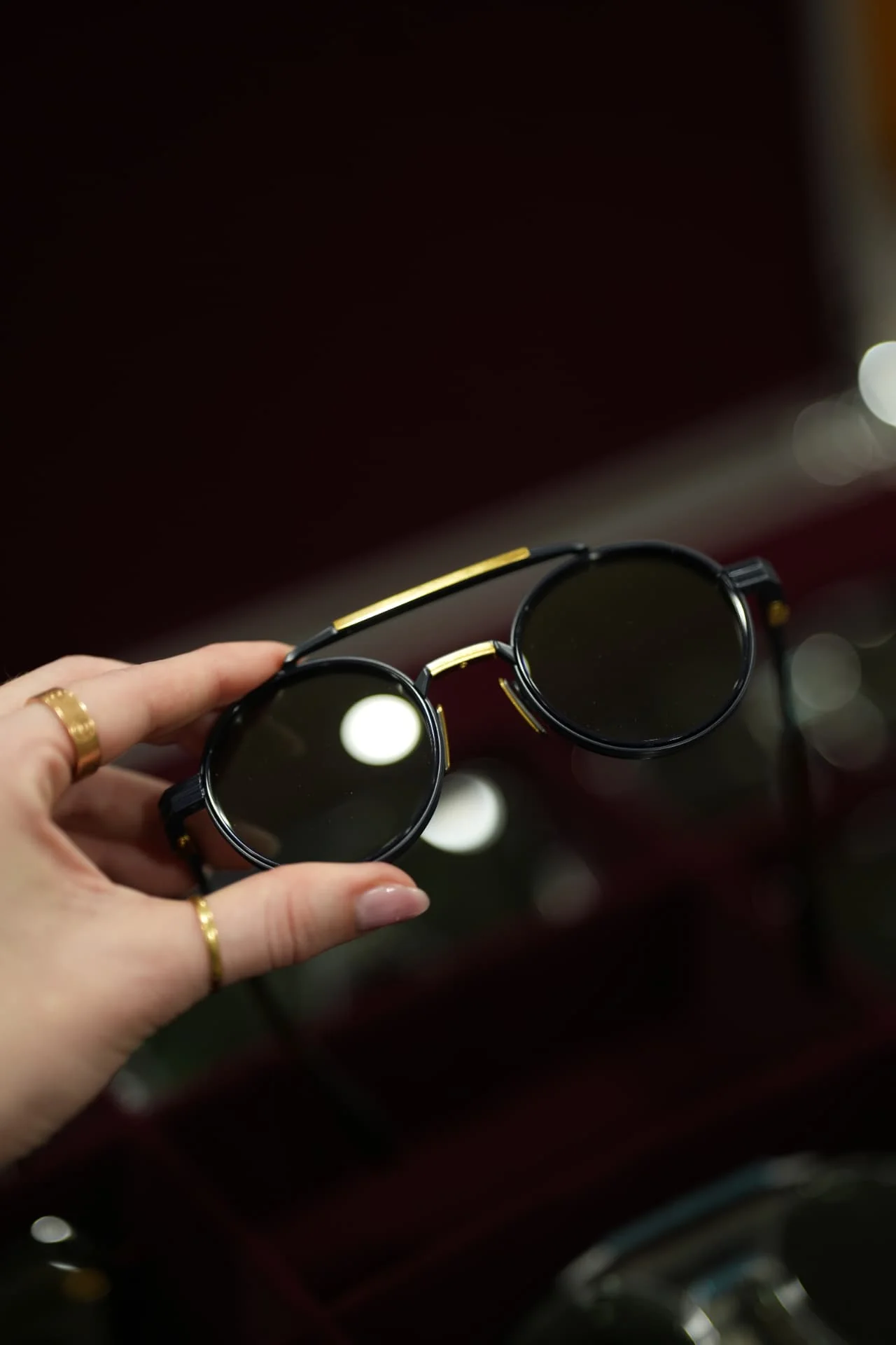 Lunettes de soleil noires et dorées présentées en main chez SKYVISION.