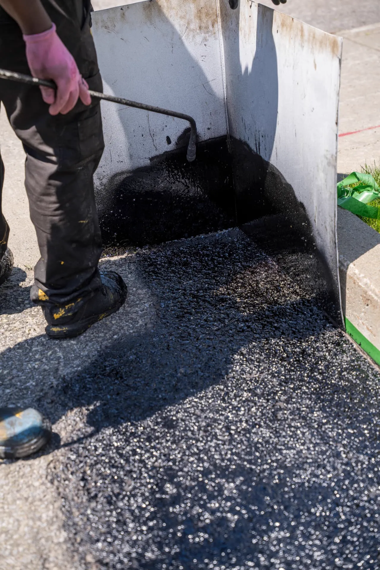 Application du scellant au balai le long d'une bordure de béton